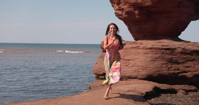 PEI Canada - July 15th 2022 - Female tourist happily runs after picture at Famous Teacup rock