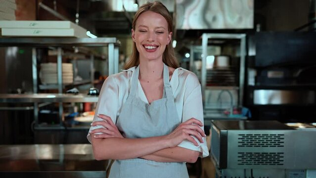 Smiling blonde female chef looking at camera in restaurant kitchen