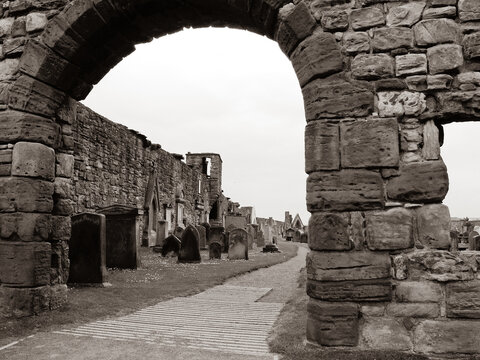 Path under stone arch in perimeter wall of graveyard