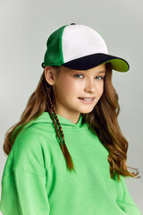 Girl in baseball cap and hoodie looks in camera smiling