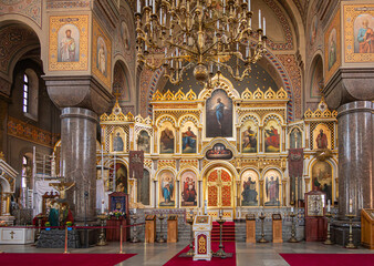 Fototapeta na wymiar Helsinki, Finland - July 20, 2022: Uspenski Cathedral. Highly decorated with paintings set in golden backdrop of reredos is main entry into sanctuary. Chandeliers, pillars, Jesus on the cross and more
