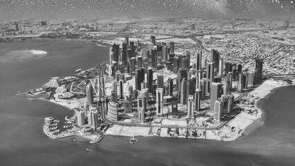 Aerial view of Doha skyline from airplane on a starry night. Corniche and modern buildings, Qatar