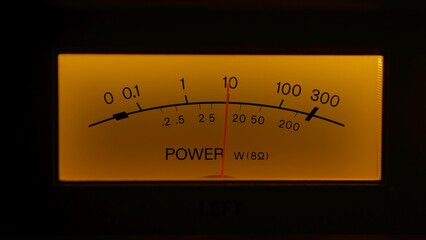 Yellow controls dashboard on an old analog radio. Close up of a scale with an arrow measuring signal power on vintage electronic sound audio device. Retro revival and nostalgia concept.