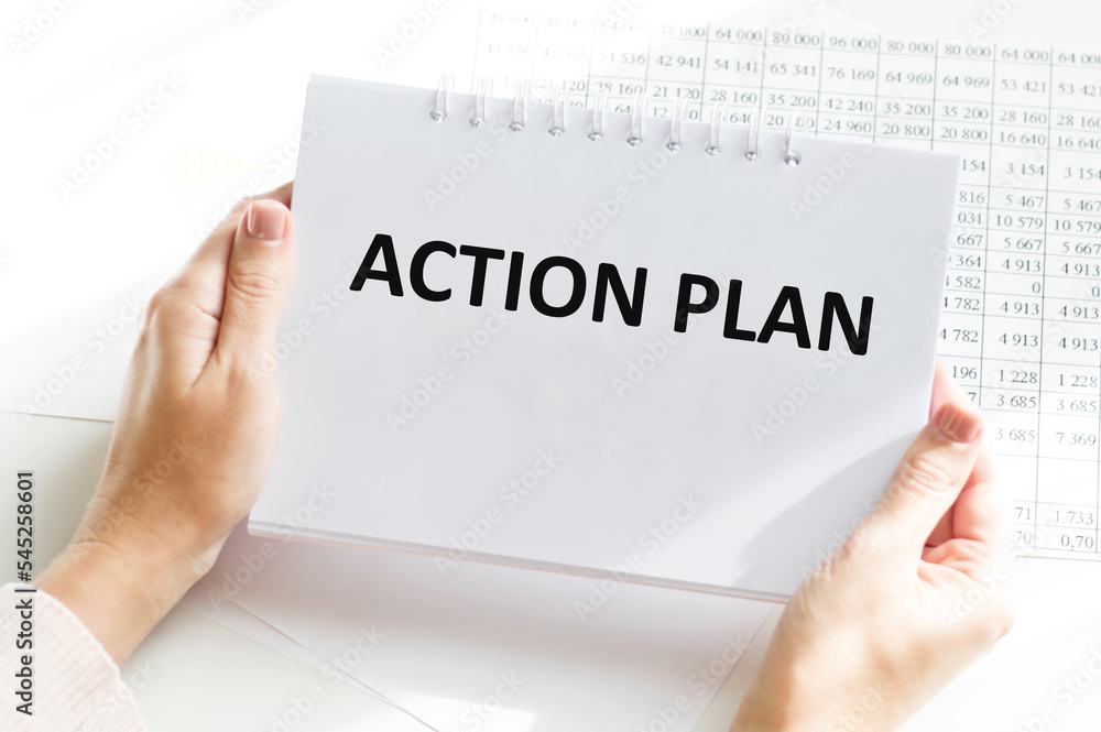 Poster a male hand holds a notepad on a spring with the written action planning text. office space. busines