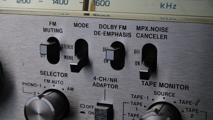 Control panel with toggle switches, knobs and buttons on a retro turntable in silver. Old analog...