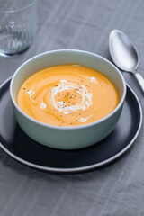 Creamy pumpkin soup garnished with  cooking sauce served in turquoise dish with slice of bread in rustic mood. Seasonal warm food. Autumn Appetiser 