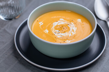 Creamy pumpkin soup garnished with  cooking sauce served in turquoise dish with slice of bread in rustic mood. Seasonal warm food. Autumn Appetiser 