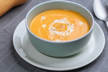 Creamy pumpkin soup garnished with  cooking sauce served in turquoise dish with slice of bread in rustic mood. Seasonal warm food. Autumn Appetiser 