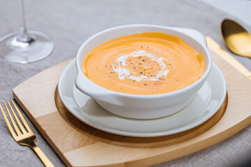 Creamy pumpkin soup garnished with  cooking sauce served in turquoise dish with slice of bread in rustic mood. Seasonal warm food. Autumn Appetiser 