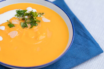 Creamy pumpkin soup garnished with  cooking sauce served in turquoise dish with slice of bread in rustic mood. Seasonal warm food. Autumn Appetiser 