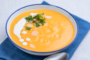 Creamy pumpkin soup garnished with  cooking sauce served in turquoise dish with slice of bread in rustic mood. Seasonal warm food. Autumn Appetiser 