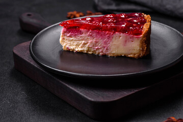 Homemade tasty cheesecake with jelly and raspberry berries on a black plate