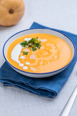 Creamy pumpkin soup garnished with  cooking sauce served in turquoise dish with slice of bread in rustic mood. Seasonal warm food. Autumn Appetiser 