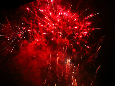 Background of glowing red fireworks exploding in the night sky on New Years Eve