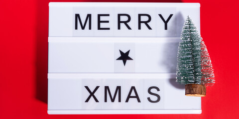 Merry Christmas greetings on lightbox on red with ornament tree