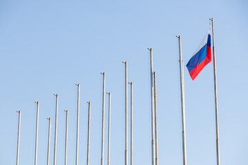 A lone Russian flag flutters against the backdrop of empty flagpoles. Metaphor for the isolation of Russia and setting an oil price cap
