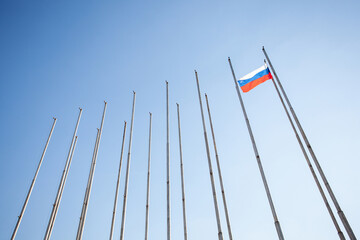 A lone Russian flag flutters against the backdrop of empty flagpoles. Metaphor for the isolation of...