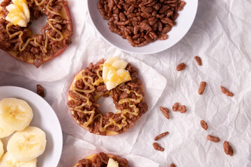 Creative party snack for holidays. Apple rounds with peanut butter, caramel and chocolate flavor puffed rice topping with banana slices. Funny appetizer for kids and adults.