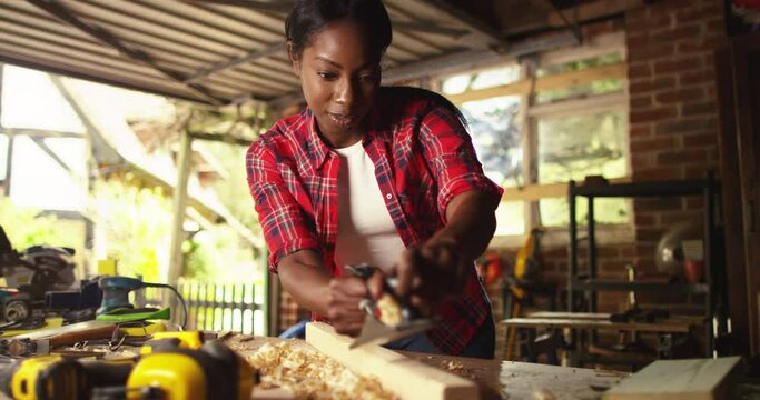 Female carpenter grinding wood with sandpaper in carpentry or diy workshop.