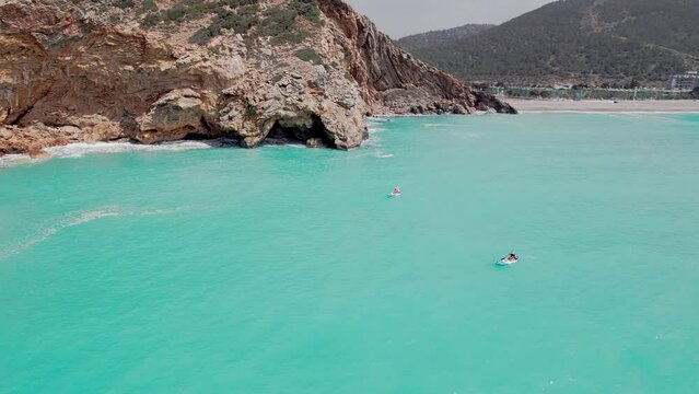 Aerial circular view of family rowing on stand up paddle boards. Mom and dad oaring on paddleboards with their sons down azure sea