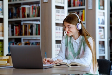 Student studying in library and listening to music