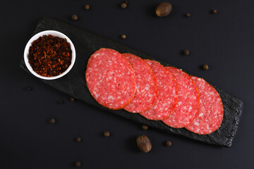 Smoked sausage slices on a black stand under dark lighting. Shallow depth of field