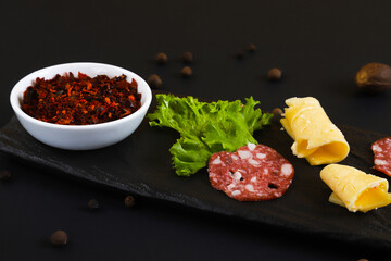 Dried adjika in a white container with other ingredients on a black stand. Shallow depth of field