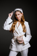 Woman in stylish white outfit holds bag looking in camera