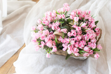 flowers in wicker basket on white wooden table, space for text. Spring blossom