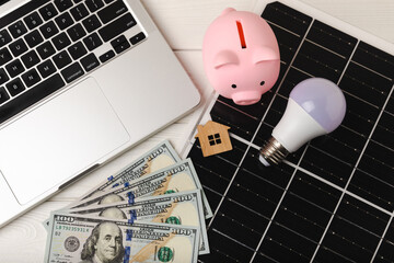 Flat lay composition with solar panel, led lamp, house model and money on  table. Money saving and...