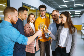 Toasting to success concept.Group of young business people toasting each other and smiling while standing in the office. Celebration and festive concept.