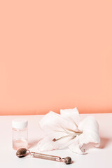 a white flower and some toothbrushs on a table with a pink wall in the background is an orange color