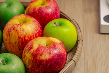 red and green apples isolated in wicker basket with wooden background