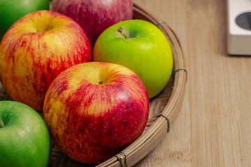 red and green apples isolated in wicker basket with wooden background