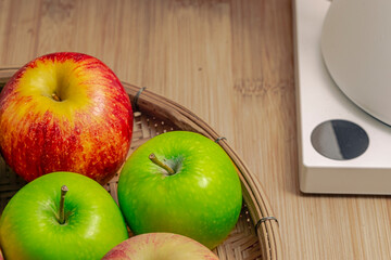 red and green apples isolated in wicker basket with wooden background