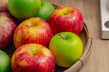 red and green apples isolated in wicker basket with wooden background
