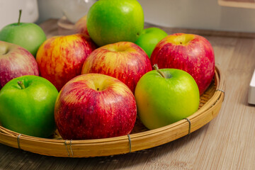 red and green apples isolated in wicker basket with wooden background