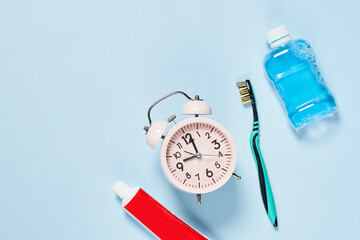 an alarm clock, toothpasn and toothbrush on a blue background with copy - to - go message