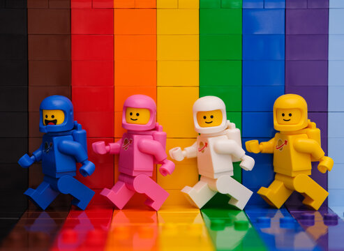 Tambov, Russian Federation - November 07, 2022 Four Lego astronaut minifigures walking in front of a rainbow backdrop