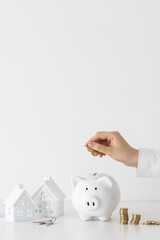 Women counting Australian Dollar coins next to a piggy bank and model house