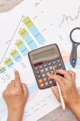 a person using a calculaant on a piece of paper with an upward graph and a pair of scissors next to the cal