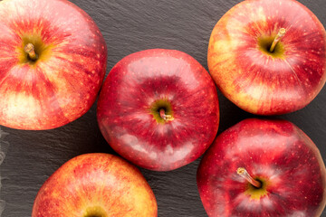 Several red juicy apples on slate stone, macro, top view.