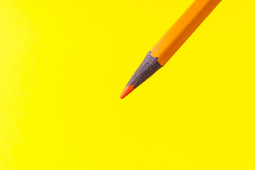 Colored pencil close-up with selective focus on the stylus and a blurred yellow background. Copy...