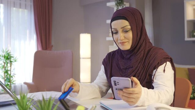 Woman in hijab shopping online.
Muslim woman in hijab places orders online with a credit card.
