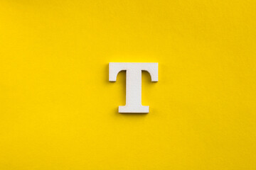 Alphabet letter T - White wood letter on yellow colored background