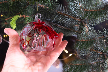 Close-up Christmas tree toy, religious plot of the birth of Christ in hand against the background...