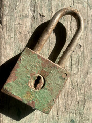 Closeup old, slightly rusty lock on a piece of plank with selective focus on foreground