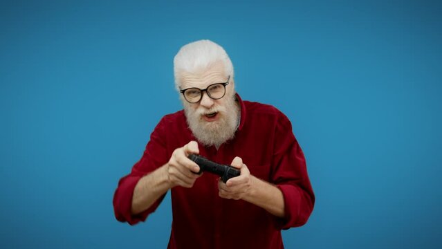 Senior man pressing buttons on joystick on blue background, video game geek