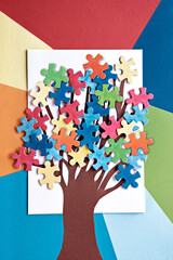 Abstract tree with colorful vibrant puzzle pieces on off white background. Autism Awareness Day,...