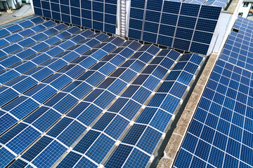 Aerial view of blue photovoltaic solar panels mounted on industrial building roof for producing...